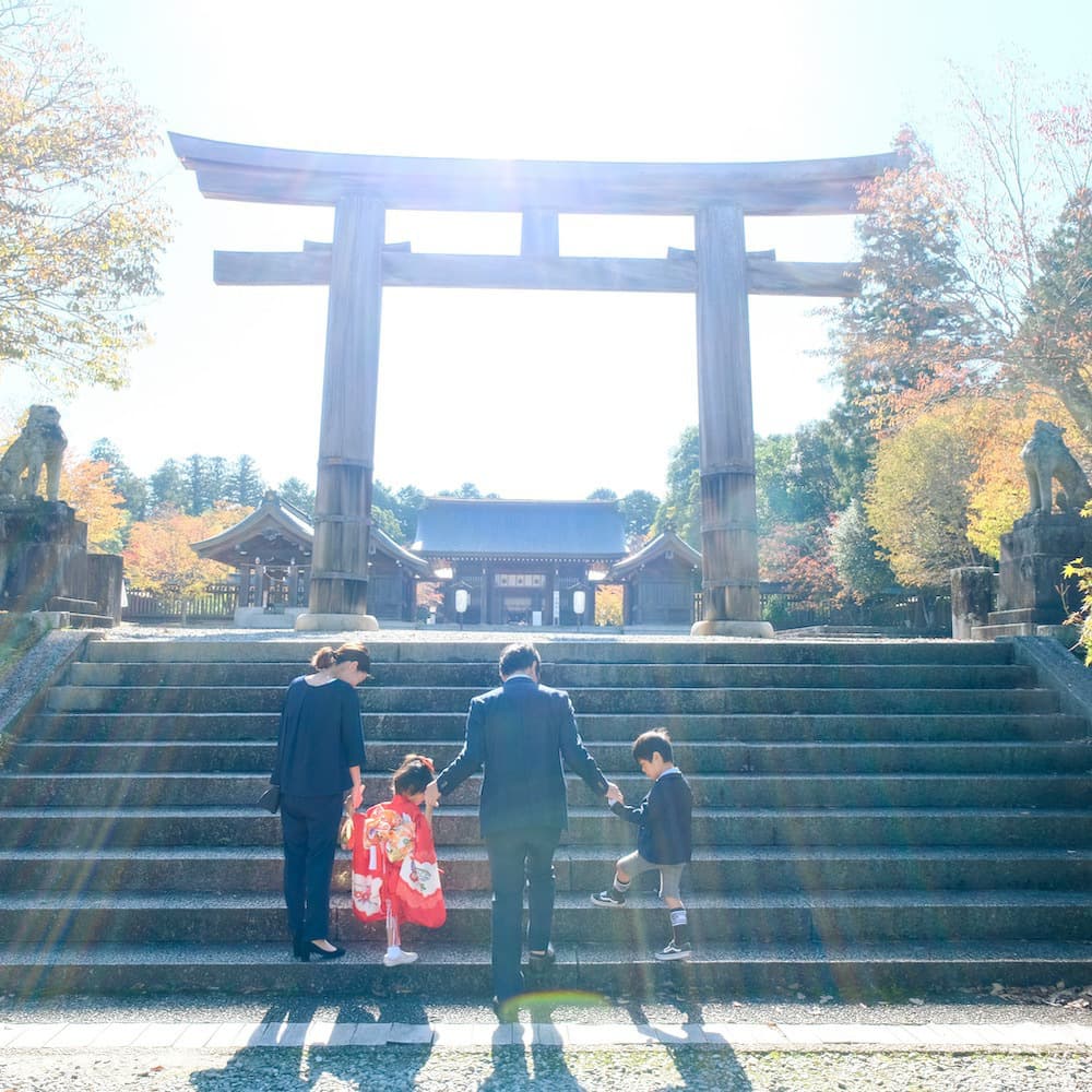 大きな鳥居に向かって歩いている七五三を祝う家族