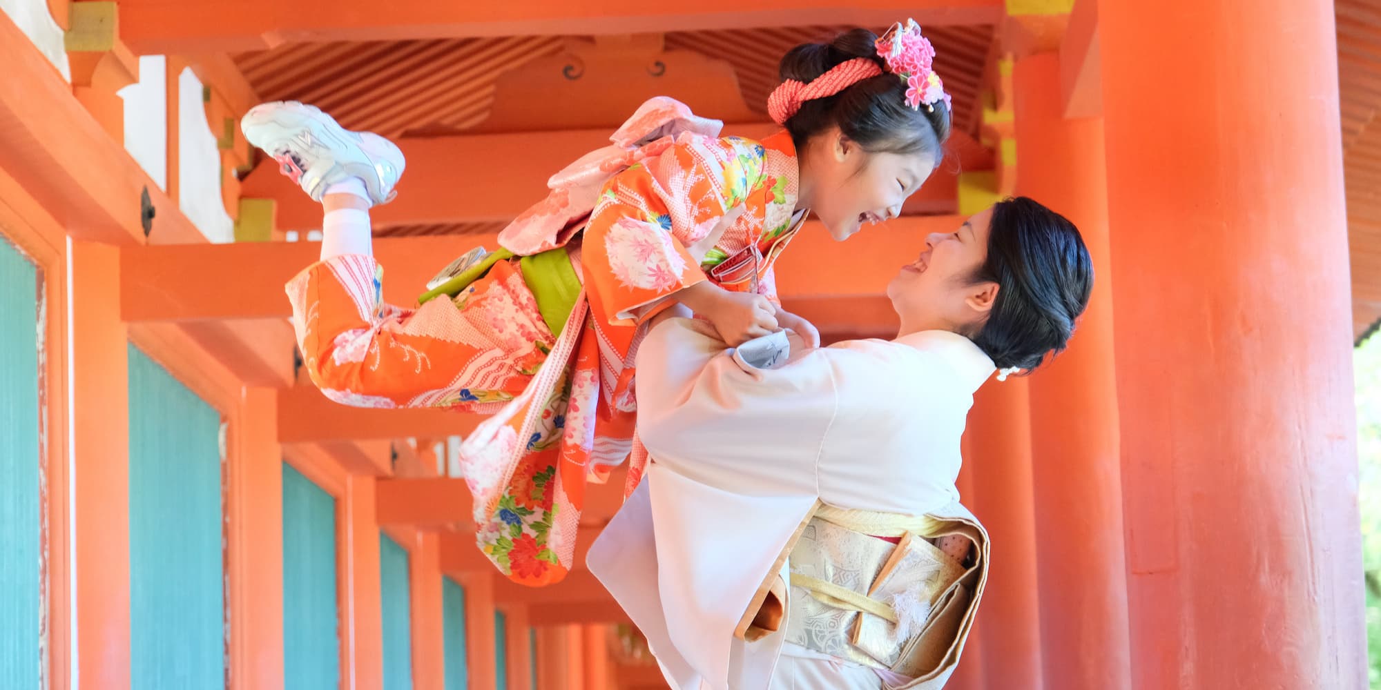 七五三の着物を着た女の子を抱き上げるお母さん