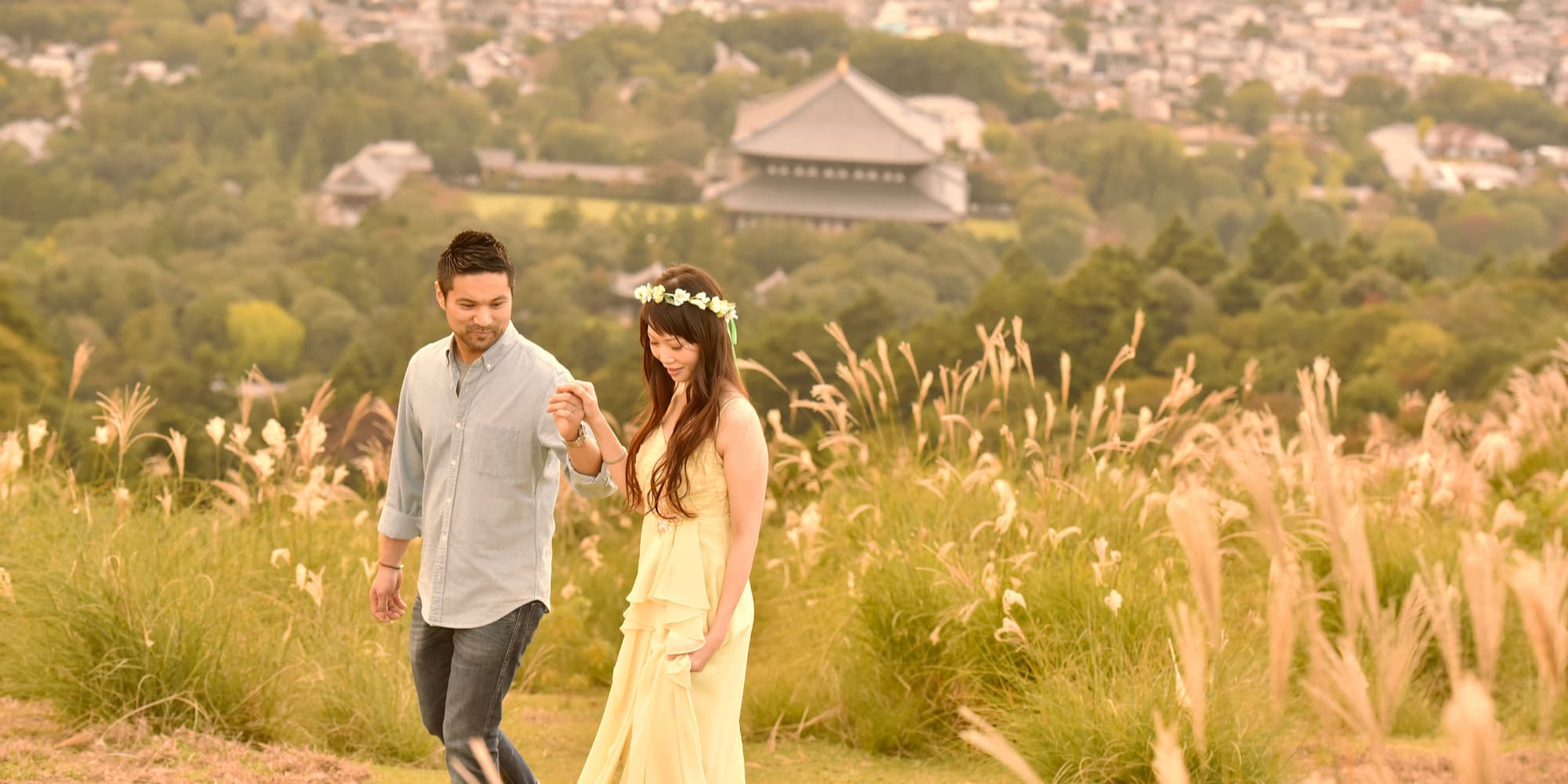 奈良のススキに囲まれた中でフォトウェディングを撮っているドレス姿の花嫁とタキシード姿の新郎